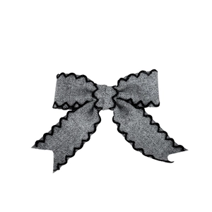 Elegant grey textile bow hair clip with decorative black wavy edge on white background