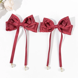 Detail of wine red satin bow hair clips with silk ribbons and pearl pendants