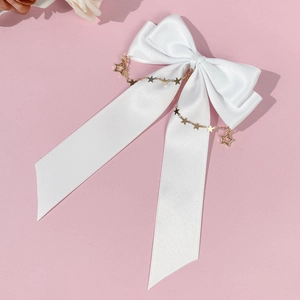 Detailed shot of white satin bow hair clip with decorative gold star pendant chains