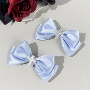 Detalle de lazos para el pelo en satén azul claro con cruz plateada y rosa roja