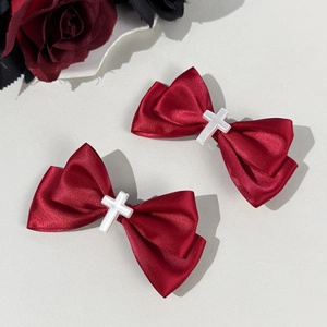 Detalle de clips de lazo de satén rojo con cruces plateadas en estilo gótico lolita