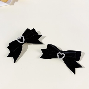 Détail de barrettes nœuds en velours noir avec centre en strass en forme de cœur