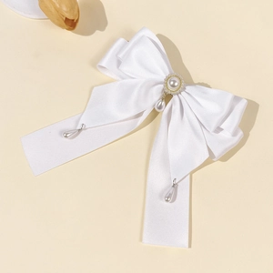 Eleganter weißer Satin-Schleifen-Haarclip mit Perlenanhängern auf weichem Hintergrund