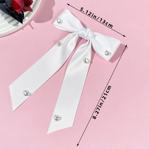 Detailed view of white satin bow hair clip with silver heart buckles on long ribbons