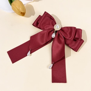 Detail der weinroten Satin-Haarschleife mit Perlenanhänger und elegantem Blumenzentrum