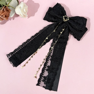 Détail d'une pince à nœud en dentelle noire avec chaînes d'étoiles dorées et cœur