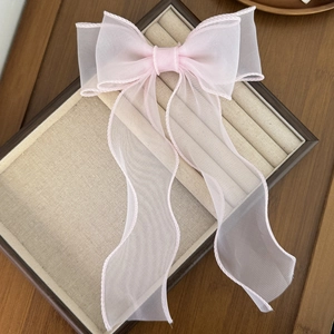 Barrette élégante en organza rose pâle avec de longs rubans sur un présentoir en lin beige