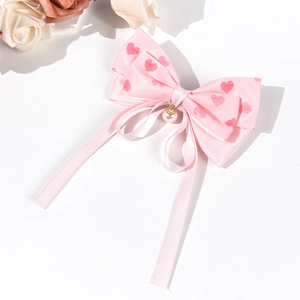 Détail de la pince à cheveux nœud rose à cœurs avec perle et longs rubans