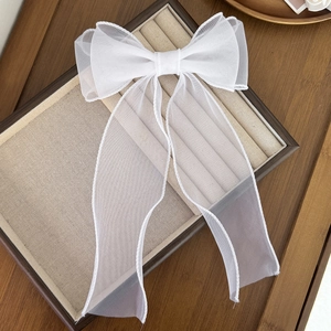 Gros plan d'une pince à cheveux avec nœud en organza blanc et longs rubans élégants