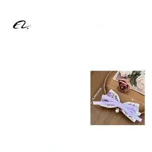 Detail view of floral embroidery bow hair clip with pearl pendant measuring 13.5x6cm