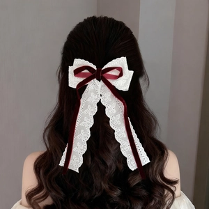 Dettaglio di fermaglio per capelli con pizzo bianco e fiocco di velluto bordeaux