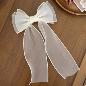 Détail d'une pince à cheveux en tulle ivoire montrant la texture délicate du tissu translucide
