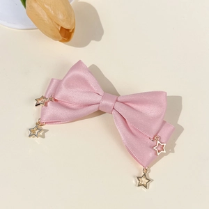 Detail view of pink satin bow hair clip with hanging gold hollow star pendants