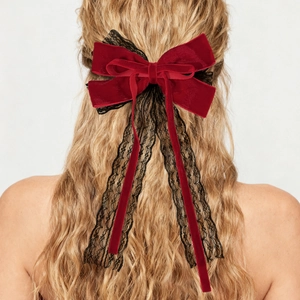 Detail of red velvet and black lace bow hair clip with long ribbons on blonde hair