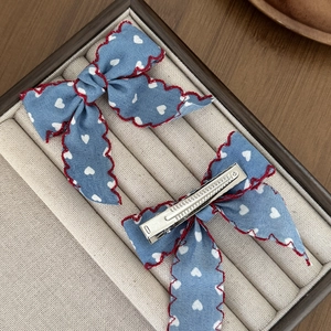 Barrettes à cheveux bleues à motifs cœurs avec bords rouges sur une boîte à bijoux
