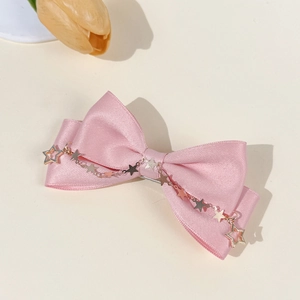 Sweet pink satin bow hair clip with metallic star chains on a clean beige background