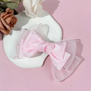 Fermaglio per capelli con doppio fiocco in rete rosa su vassoio decorativo