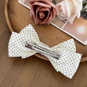 Sweet polka dot bow hair clip for girls with a vintage floral background on wood