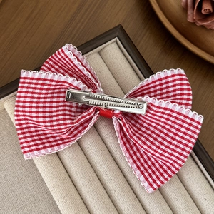 Sweet red and white plaid bow hair clip with lace trim on a beige jewelry display tray