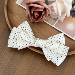 Detailed macro view of white polka dot layered ribbon hair clip on vintage wooden tray