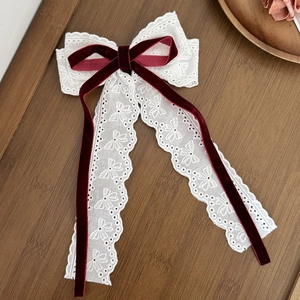 Dettaglio del fiocco per capelli in pizzo bianco con nastro di velluto bordeaux lucido