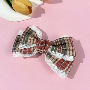 Detail of vintage plaid bow hair clip with white lace trim and colorful checkered pattern