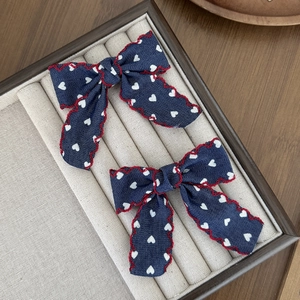 Vue détaillée de nœuds pour cheveux bleus à motifs de cœurs et broderie rouge festonnée