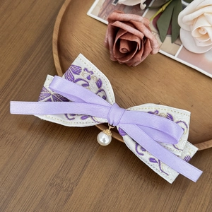 Detailed view of lavender ribbon bow hair clip with floral embroidery and pearl pendant