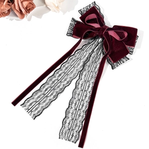 Detailed texture of burgundy velvet and black lace bow hair clip with long ribbons