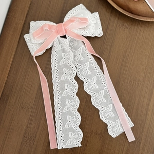 Dettaglio ravvicinato del fiocco in pizzo bianco con piccoli nastri in velluto rosa