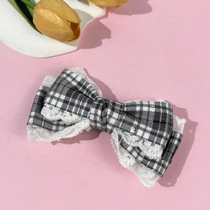Detail of plaid bow hair clip with lace trim and silver sequins on pink background