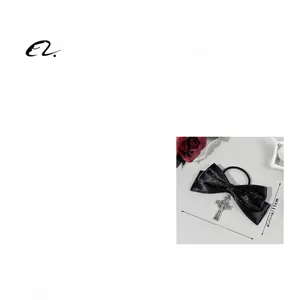 Detail of black satin bow hair tie with a silver gothic cross pendant and smooth texture