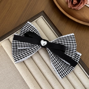 Sweet plaid bow hair clip with lace trim and heart charm on a jewelry tray