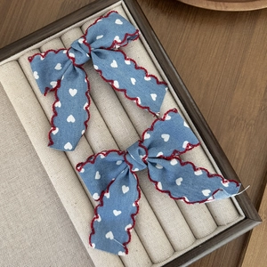 Gros plan de barrettes à nœuds bleus avec motifs cœurs et coutures rouges