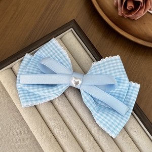 Detail of light blue plaid bow hair clip with lace edge and heart-shaped center pearl