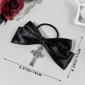 Detailed macro view of black satin bow hair tie with silver metallic crucifix pendant