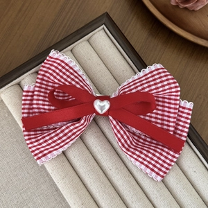 Detail of red plaid bow hair clip with white lace trim and heart pearl center