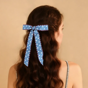 Blue denim style bow hair clip with heart print shown on a model's long brown hair