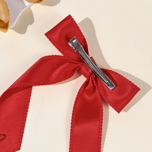 Elegant red satin bow hair clip with serrated edges and metal duckbill clip for women