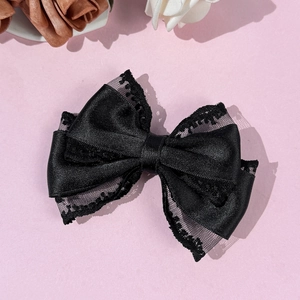Close-up of black lace bow hair clip with elegant satin texture and floral patterns