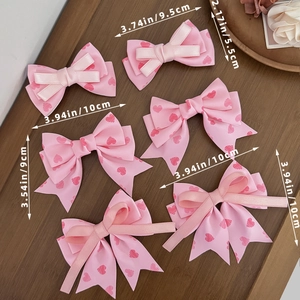 Ensemble de barrettes à nœuds roses avec motifs cœurs sur fond en bois