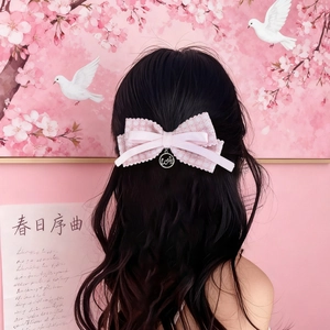 Pink plaid lace bow hair clip with love pendant worn by woman on pink background