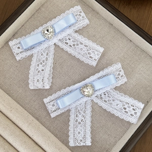 Detailed macro view of light blue lace bow hair clips with heart-shaped crystal centerpieces