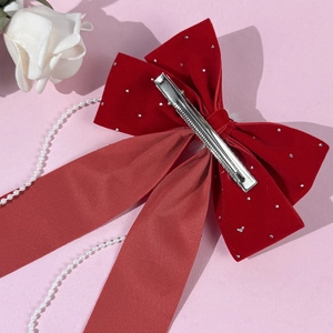 Red velvet bow hair clip with silver rhinestones and long ribbons on pink background
