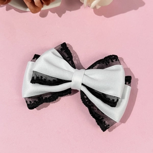 Detail of white satin hair bow with black lace trim and multi-layer elegant design