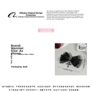 Détail du nœud en dentelle noire avec pendentifs cœur et croix, dimensions 11cm x 7,5cm