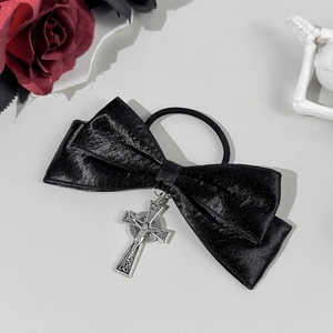 Detailed close-up of a black satin bow hair tie with a silver gothic cross pendant