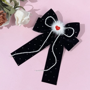 Detail of black velvet hair bow with red heart center and elegant pearl chain tassels