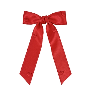 Red satin bow hair clip with heart accents and long ribbons on a white background