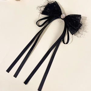 Detail of black bow hair clip featuring lace tassels, shimmering silver particles and a pearl